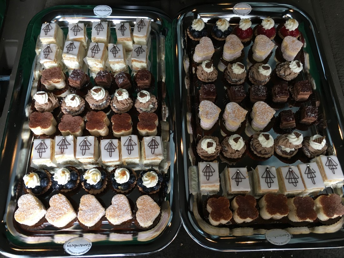 Silbertabletts voller Mini-Patisserie: Cremeschnitten, Törtchen und Pralinés
